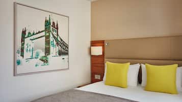 A hotel room with a bed, a headboard, a wall-mounted lamp, and a framed picture of a bridge.