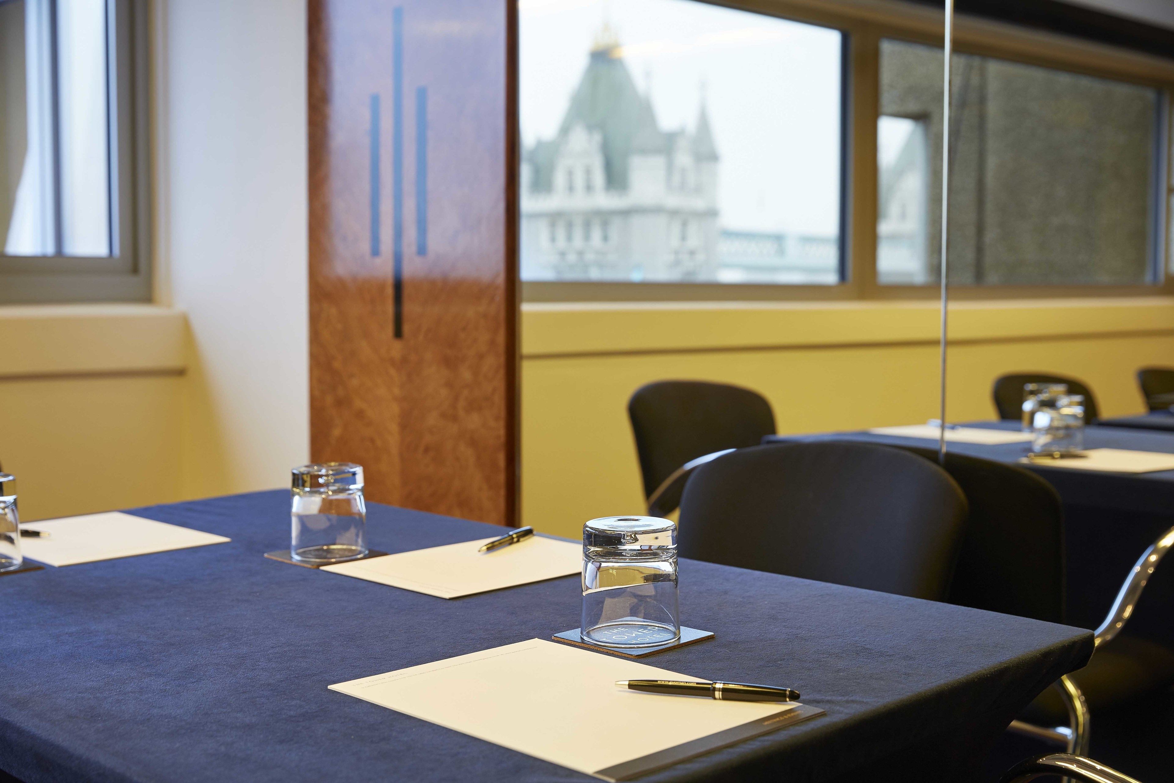 A conference room with tables set up for meetings, equipped with pens, notepads, and glasses of water.