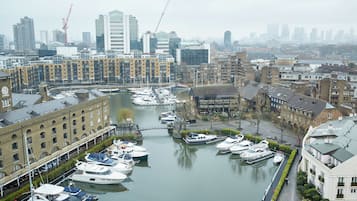 A marina with boats docked, surrounded by buildings and a city skyline in the background.