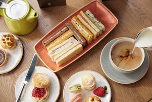 Ein Tisch mit Sandwiches, Scones und einer Teekanne.