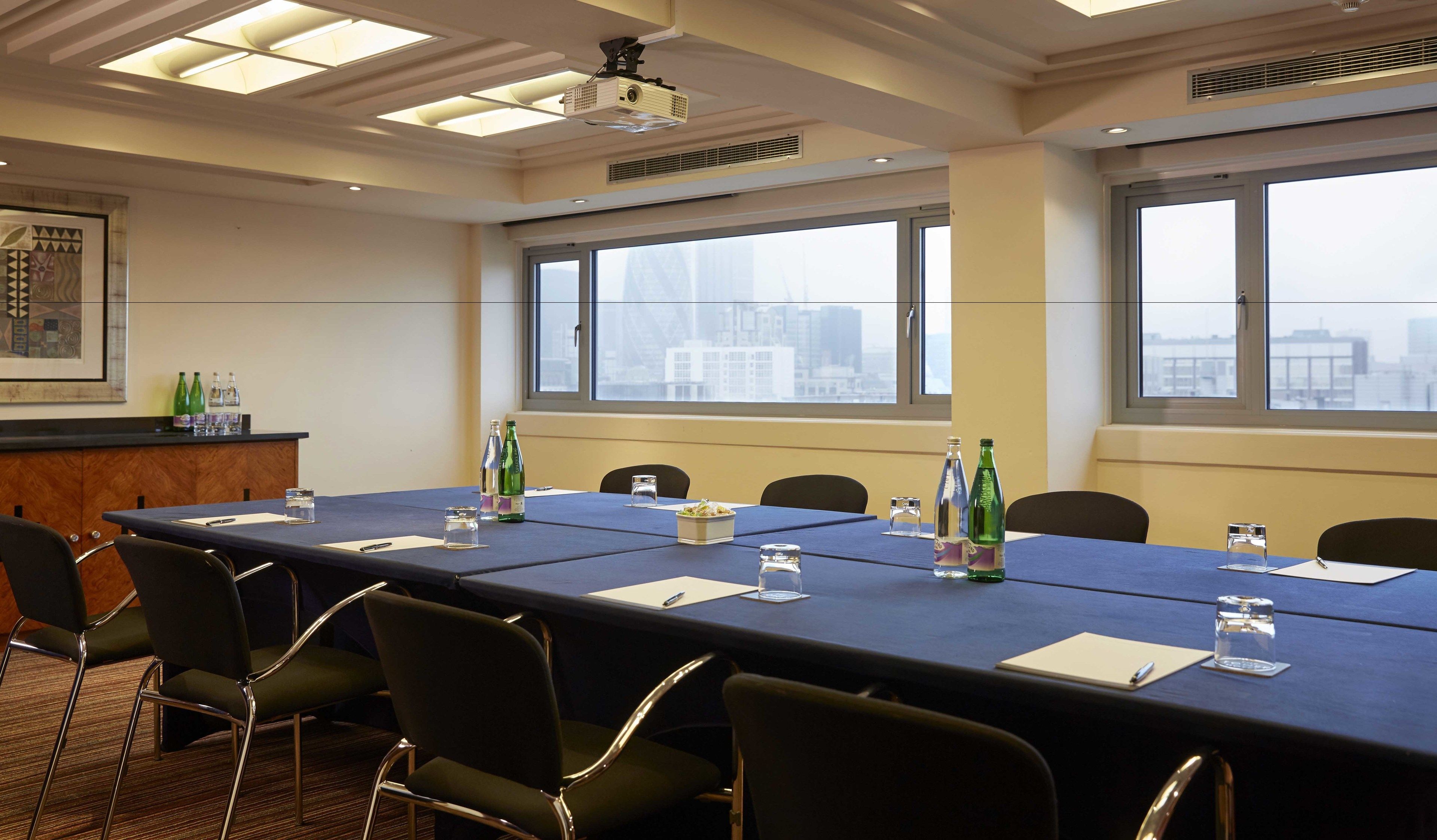 A conference room with a long table, chairs, water bottles, and a projector.