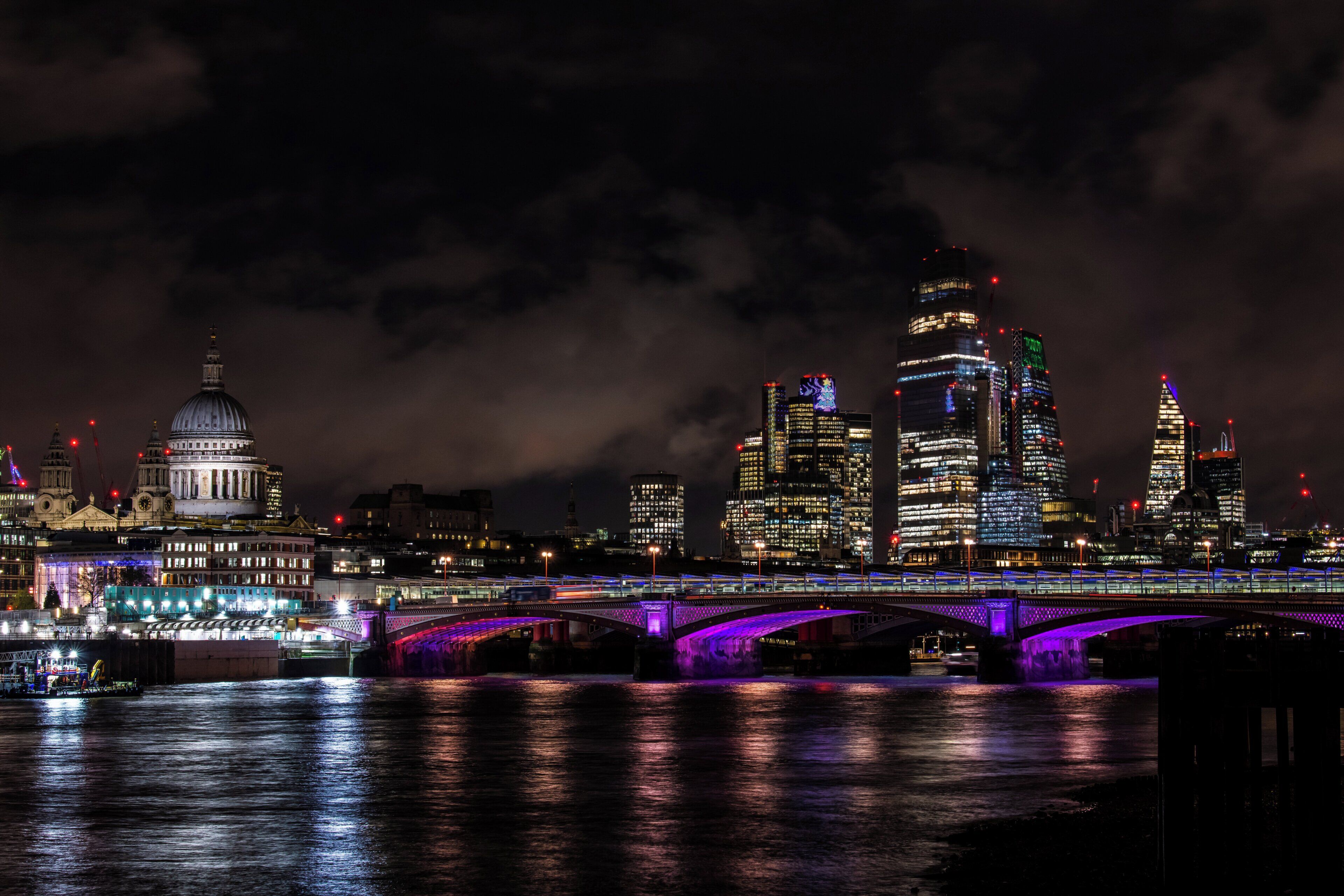 A nighttime cityscape with a prominent bridge and illuminated buildings.