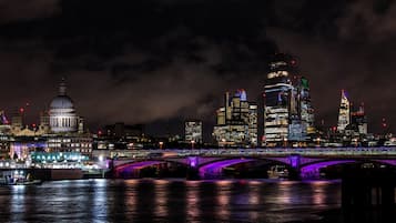A nighttime cityscape with a prominent bridge and illuminated buildings.