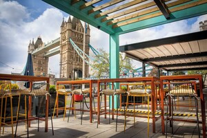 Outdoor seating with tables and chairs, a view of a historic tower, and a covered area with a roof.