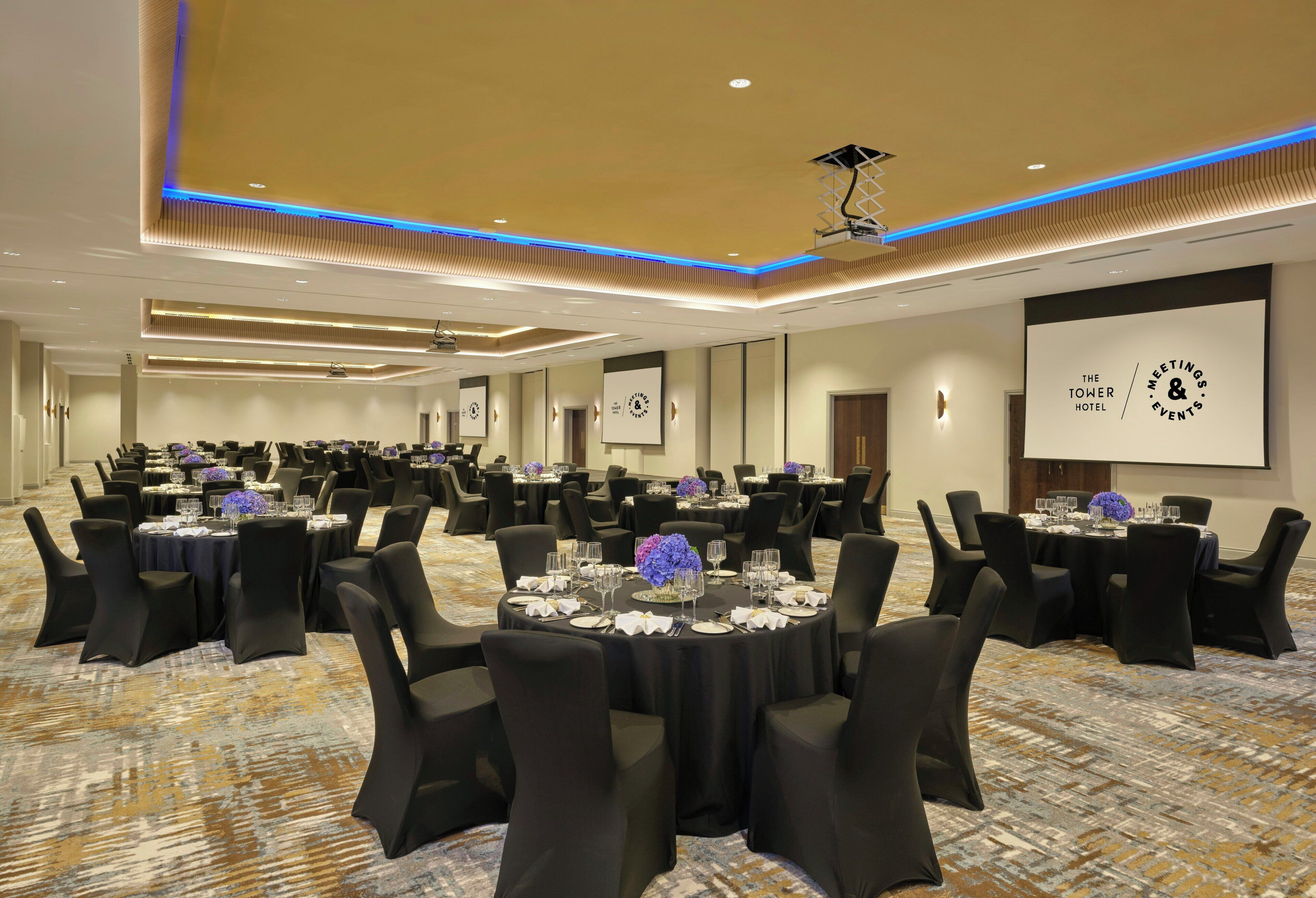 A large conference room with multiple tables set for meetings, equipped with projectors and screens for presentations.