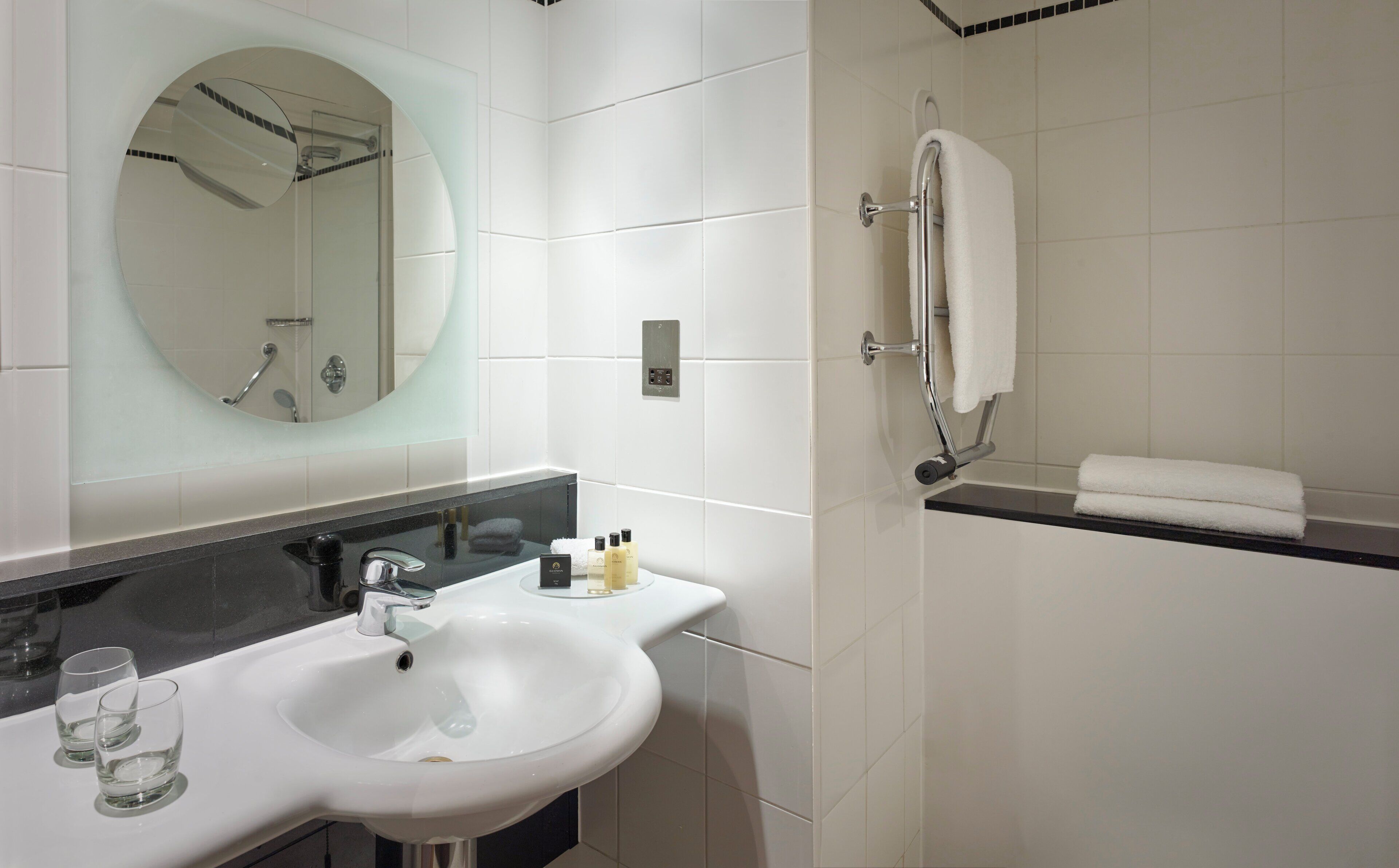 A bathroom with a white sink, mirror, and shower.