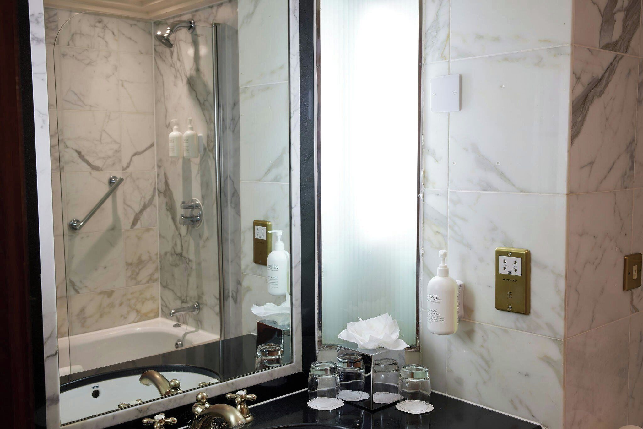 A bathroom with a bathtub, a shower, a sink, and a mirror.