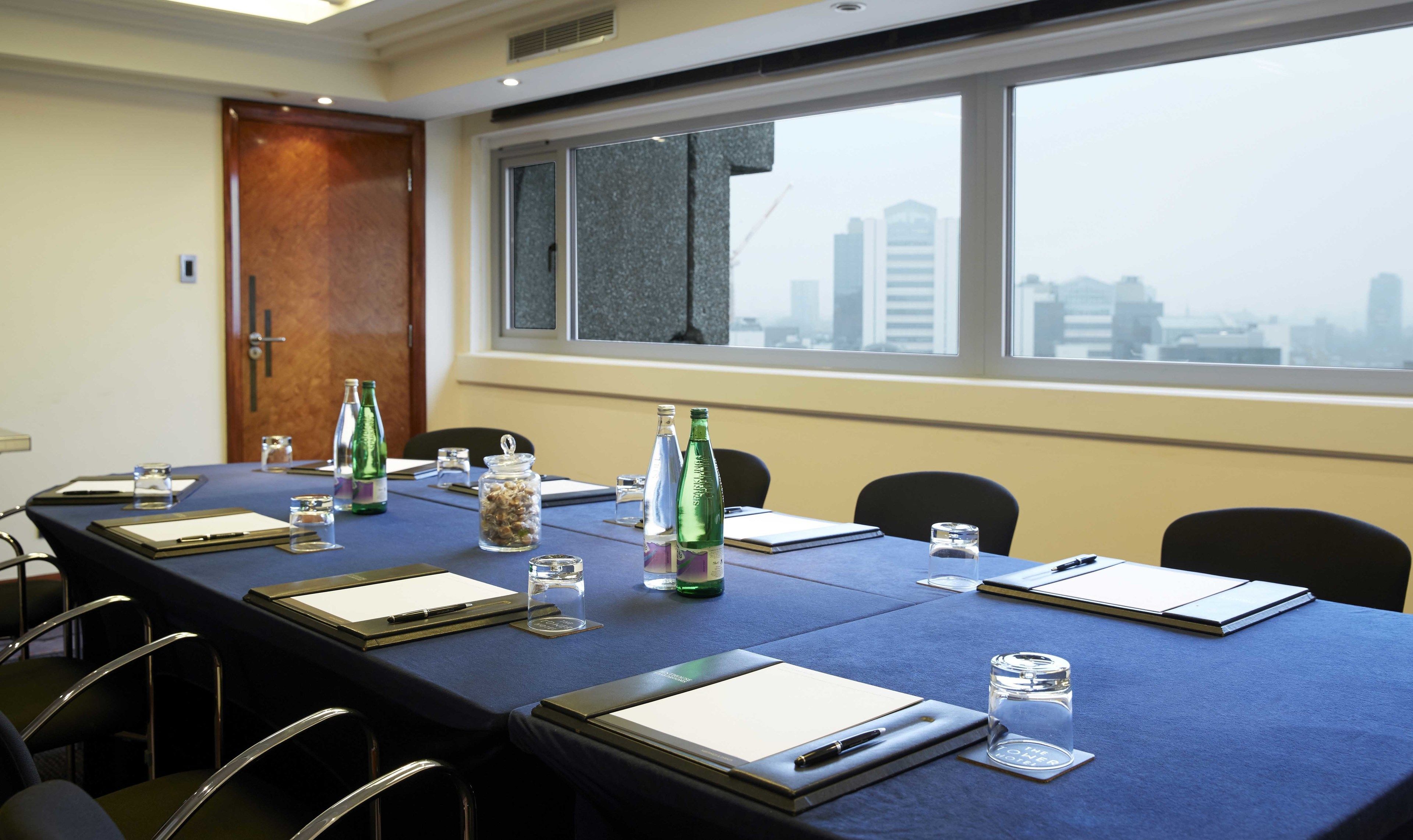 A conference room with a long table, chairs, and a window with a city view.