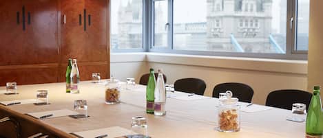 A conference room with a long table, chairs, and a view of a historic building through large windows.