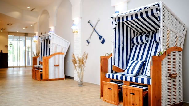 Two striped wicker daybeds in a bright room with wooden flooring and white walls. - Dorint Hotel Alzey/Worms (Alzey)