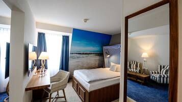 Habitación de hotel con cama, escritorio con lámpara, silla, sofá y un espejo grande.