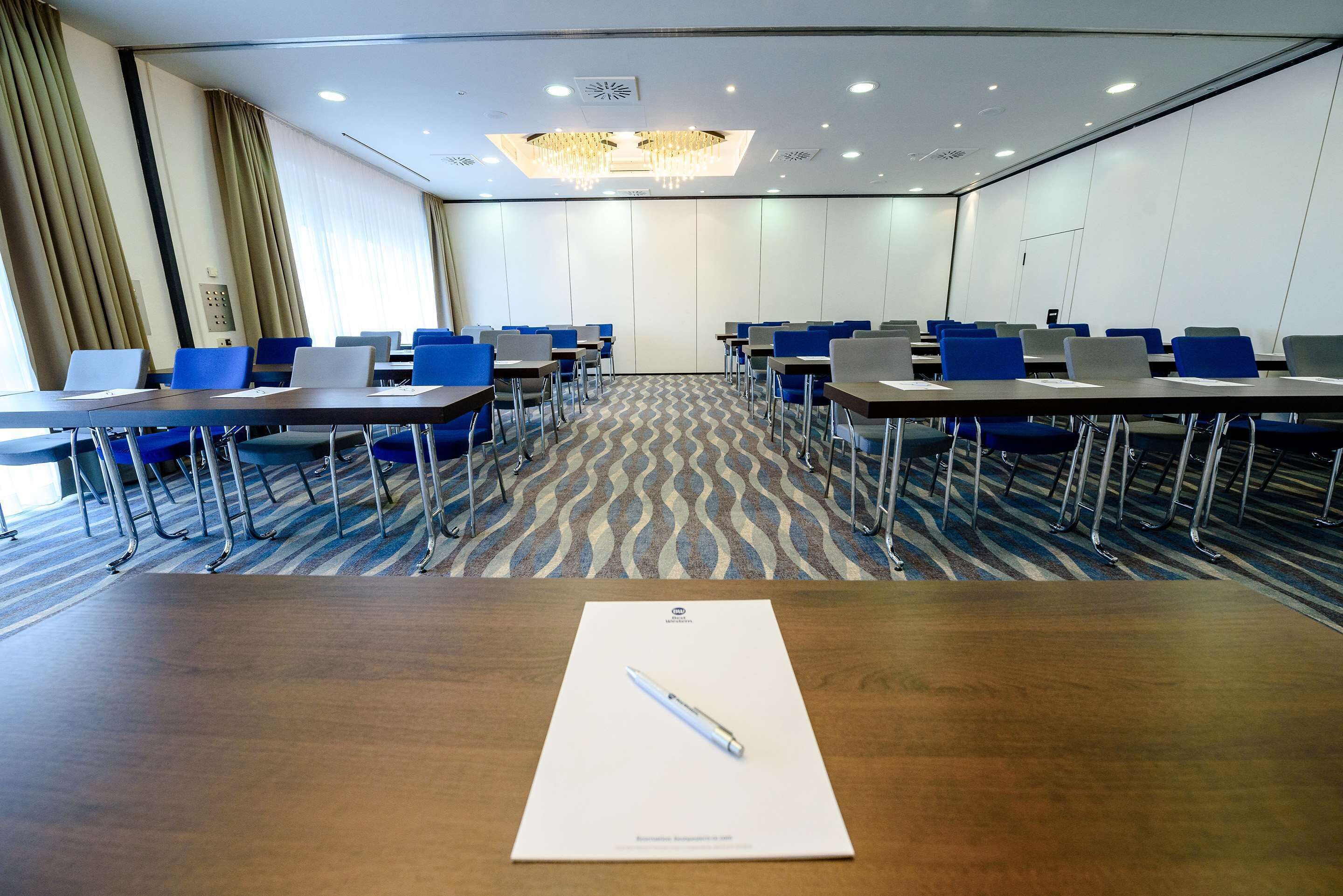 A conference room with a long table, blue chairs, and laptops.
