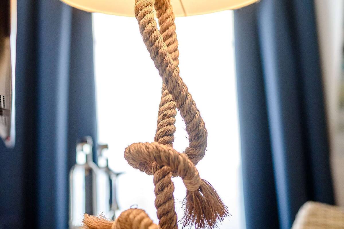Eine Lampe mit Kordelbasis und beiger Lampenschirm, auf einer Holztischplatte abgestellt.