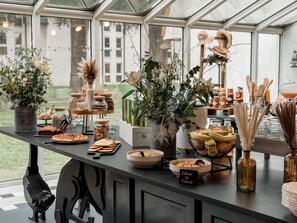Ein übersichtlich gestalteter Buffetstisch mit verschiedenen Speisen und dekorativen Pflanzen.