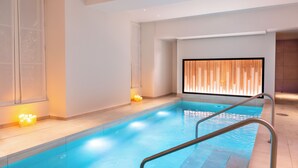 Ein moderner, überdachter Pool mit freier Sicht, einer Wand aus Holzpaneelen und einer Metallleiter.
