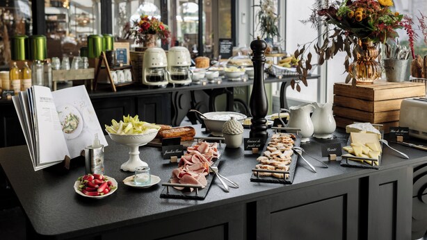 Ein reichhaltiges Buffet mit verschiedenen Speisen, einer Speisekarte und dekorativen Elementen wie Blumen und Kerzen.