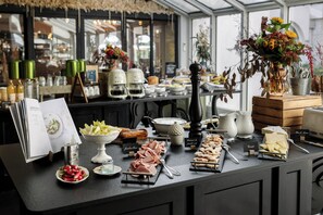 A buffet setup with various food items, a menu, and decorative elements like flowers and candles. - Demeures de campagne Parc du Coudray – Mercure (Le Coudray-Montceaux)