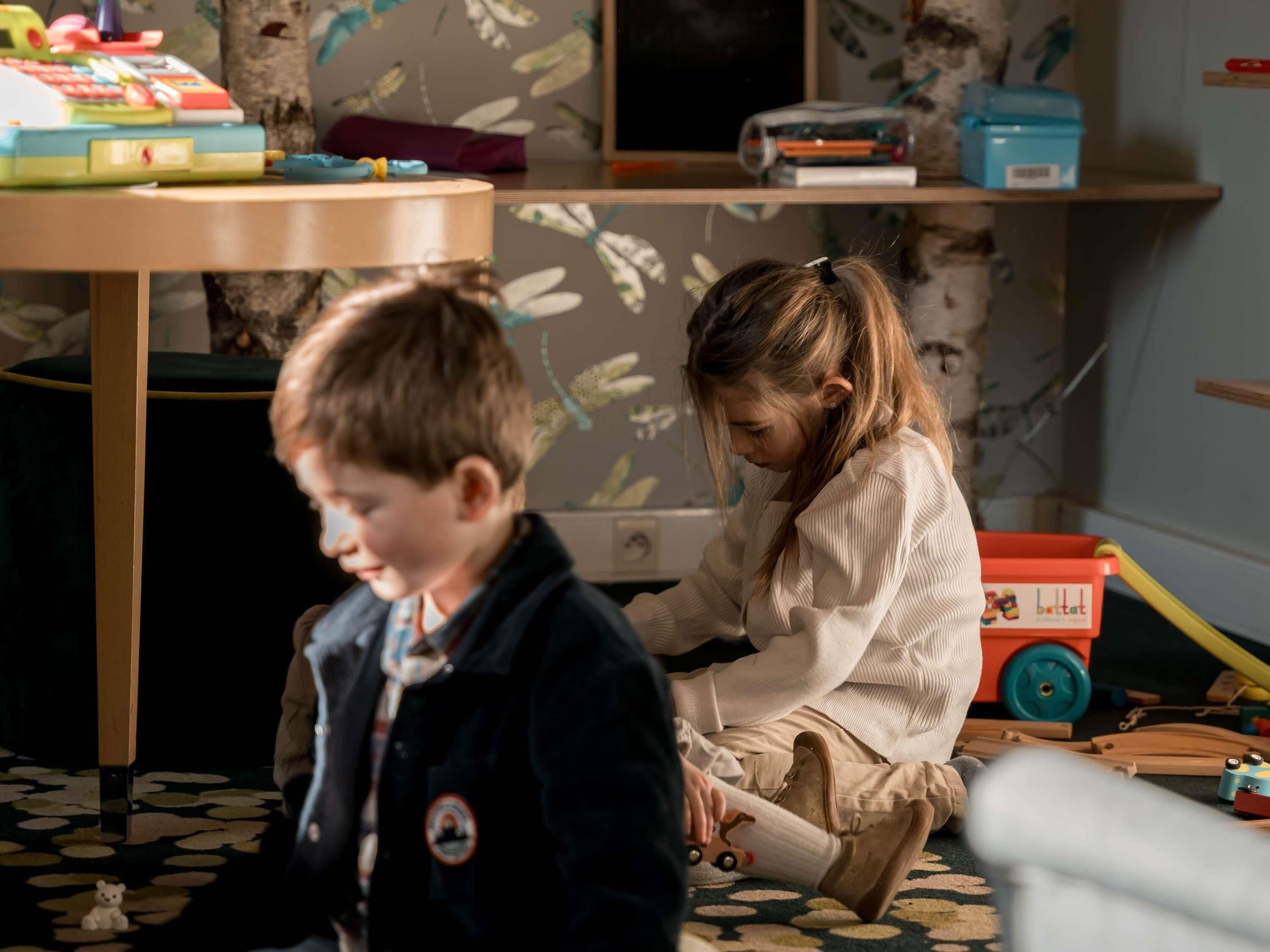 Une pièce avec une table en bois, une chaise et un enfant qui joue avec des jouets.