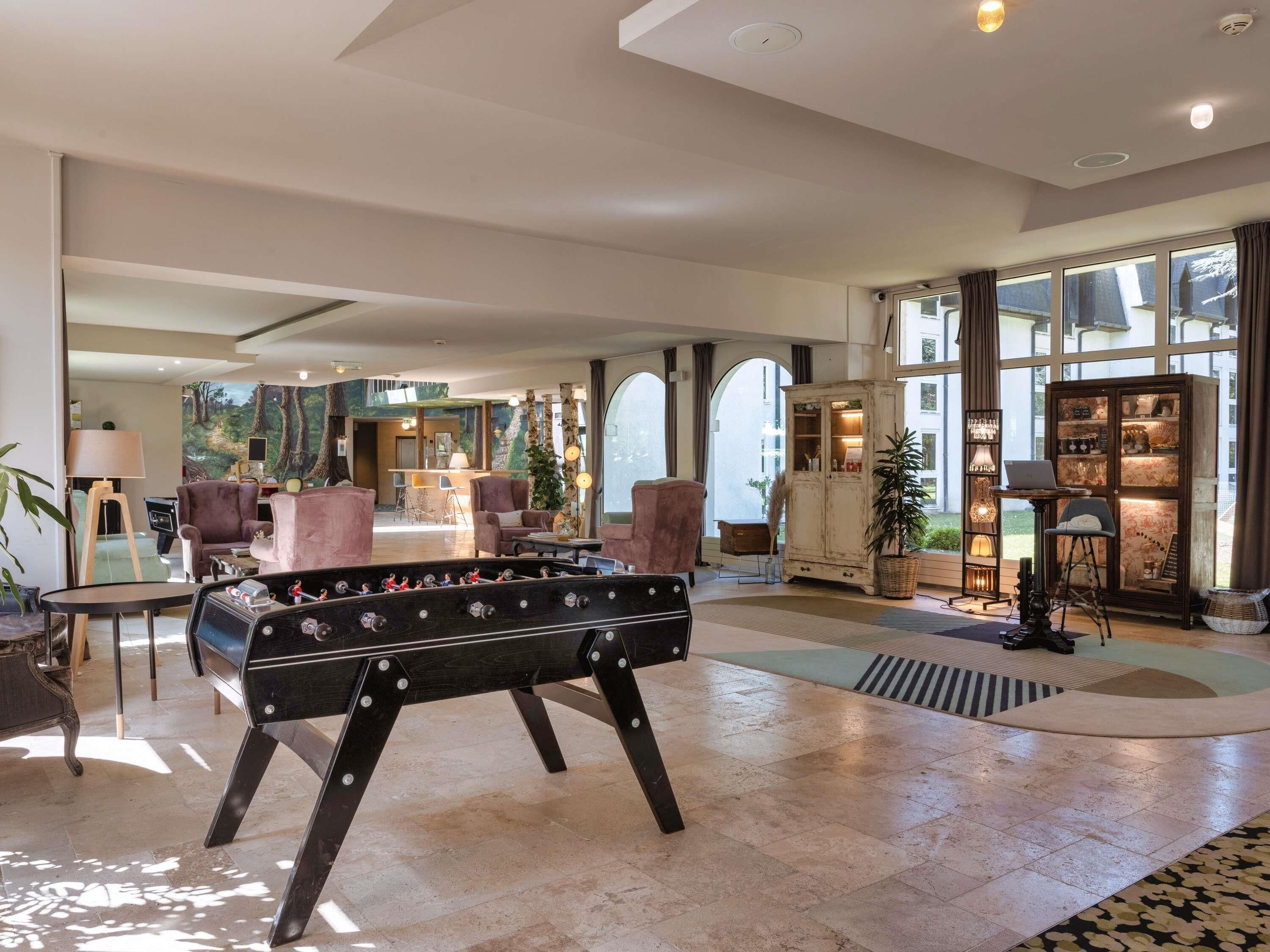 A spacious lobby with a foosball table, seating area, and large windows.