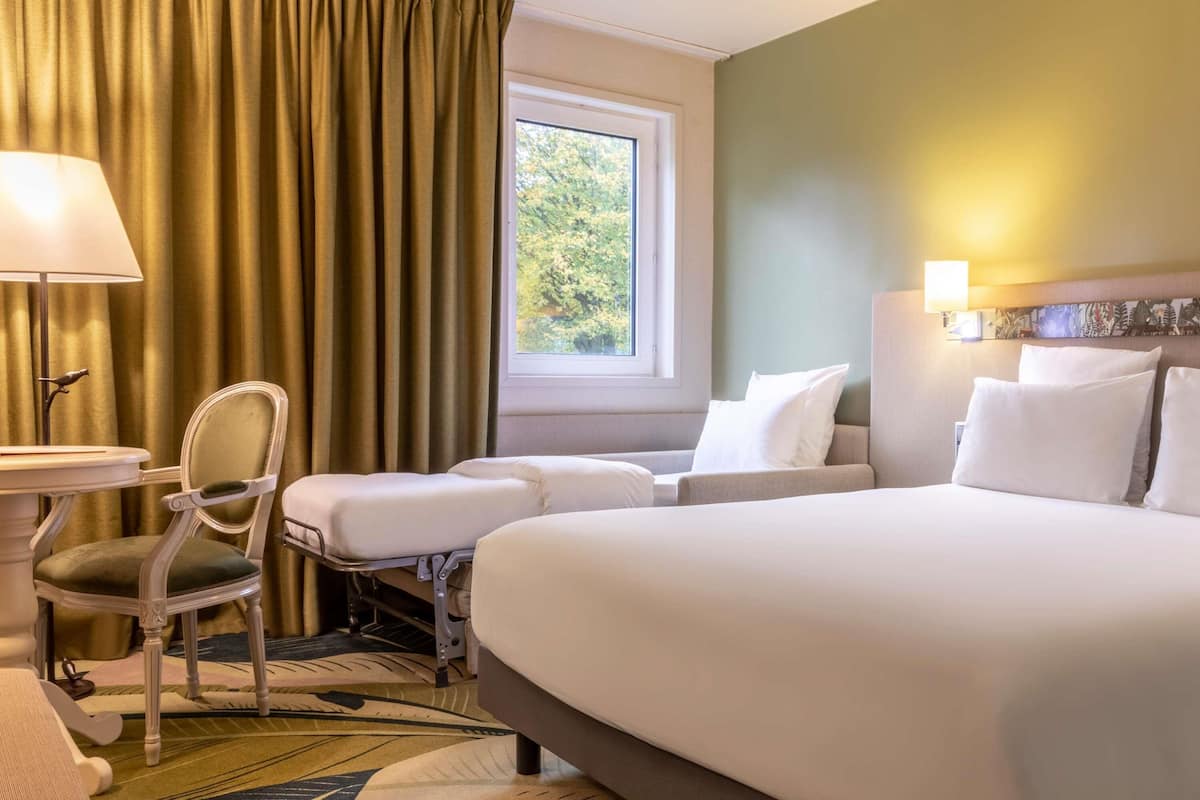 Une chambre d’hôtel avec un lit, une chaise, une table et une fenêtre.