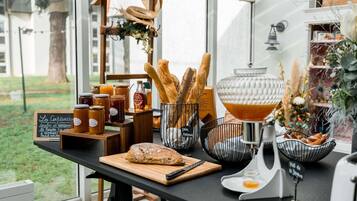 Interior de una cafetería con una variedad de pan, pasteles y frascos de miel a la vista.