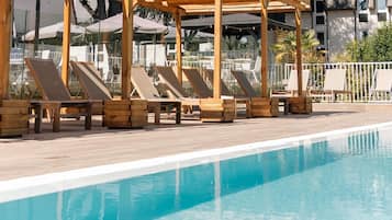 Una piscina al aire libre de temporada, sillones reclinables de piscina