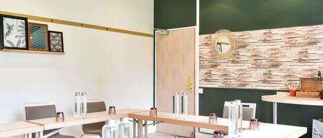 Un salón de conferencias con mesas largas, sillas y un espejo decorativo en la pared.