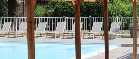 Una piscina al aire libre de temporada, sillones reclinables de piscina