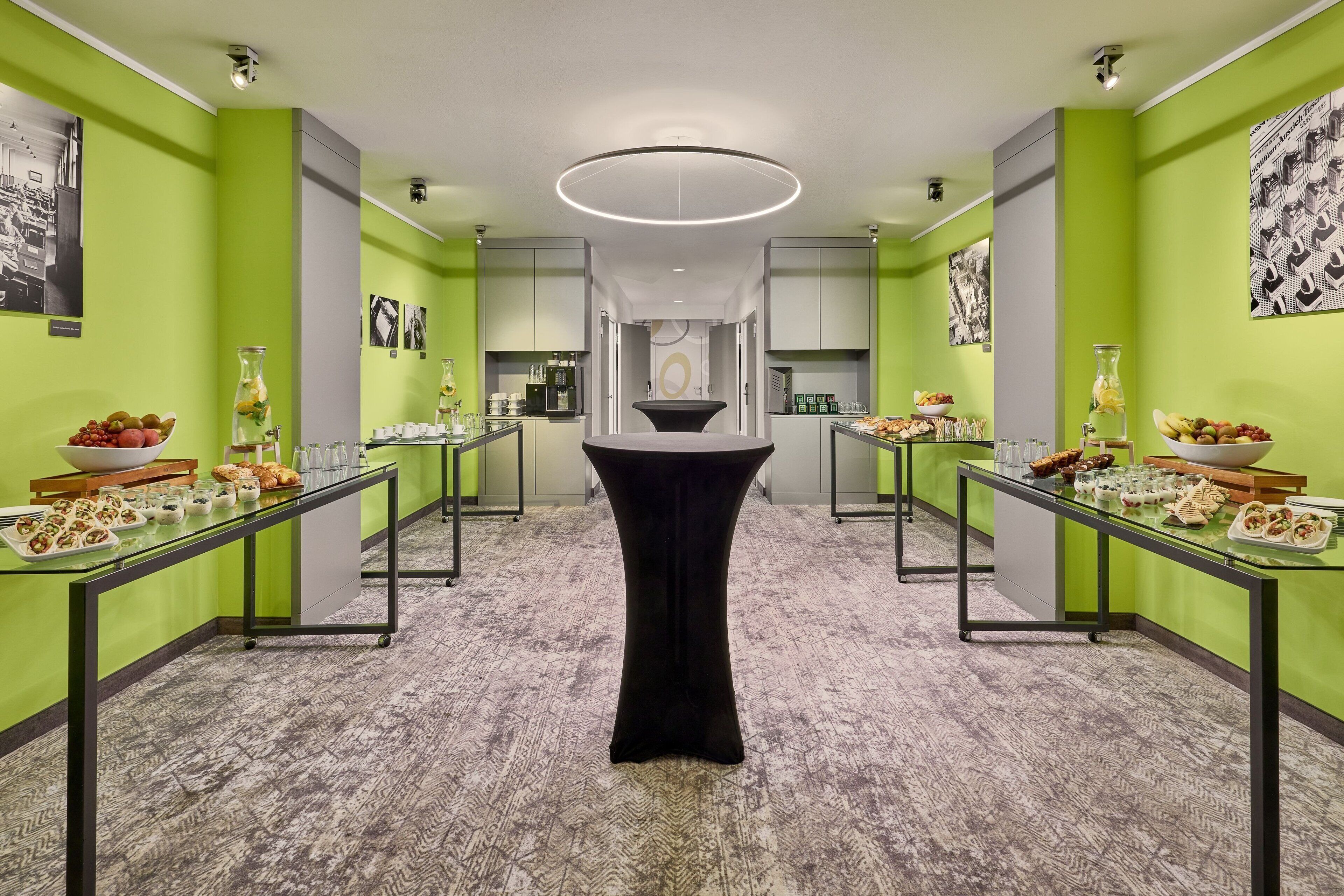 A modern hotel corridor with green walls, a central black table, and glass railings.
