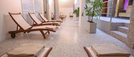 Zona de spa con sillones de sol y una planta en maceta.