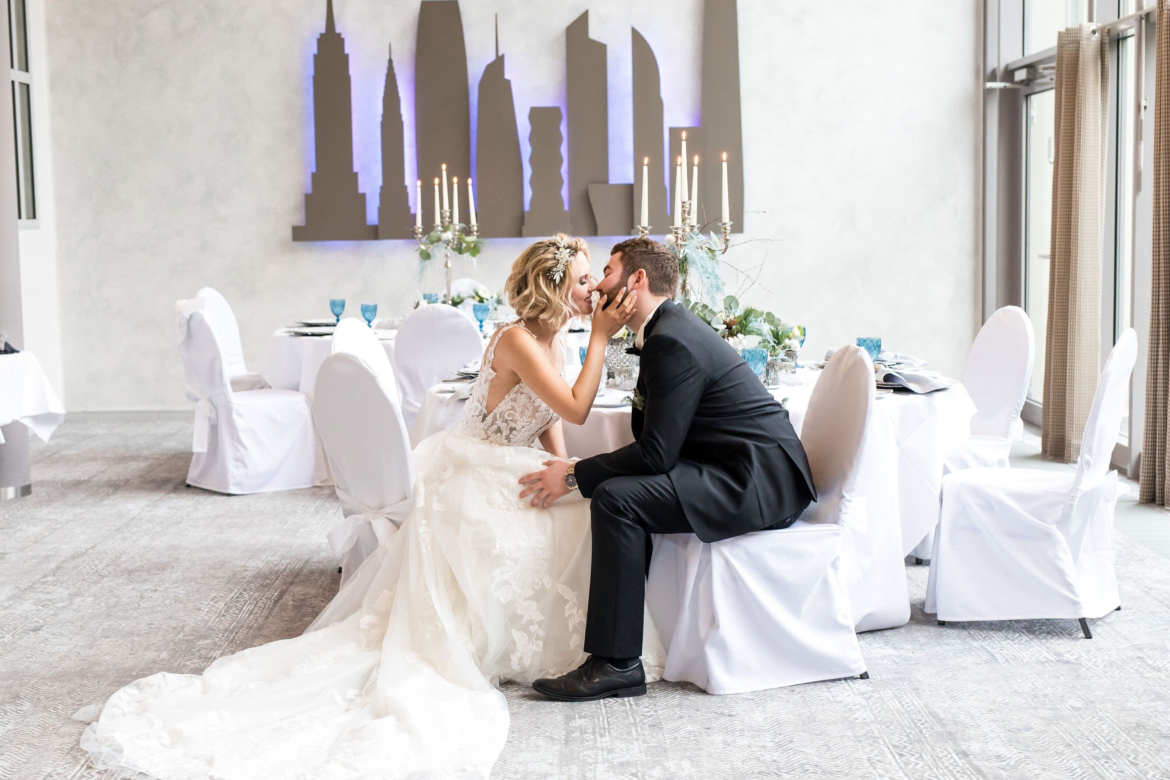 A wedding reception with a modern interior, white decor, and a cityscape silhouette on the wall.