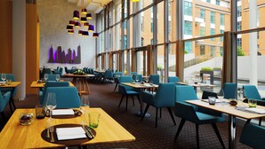 A modern restaurant with large windows, blue chairs, and wooden tables.