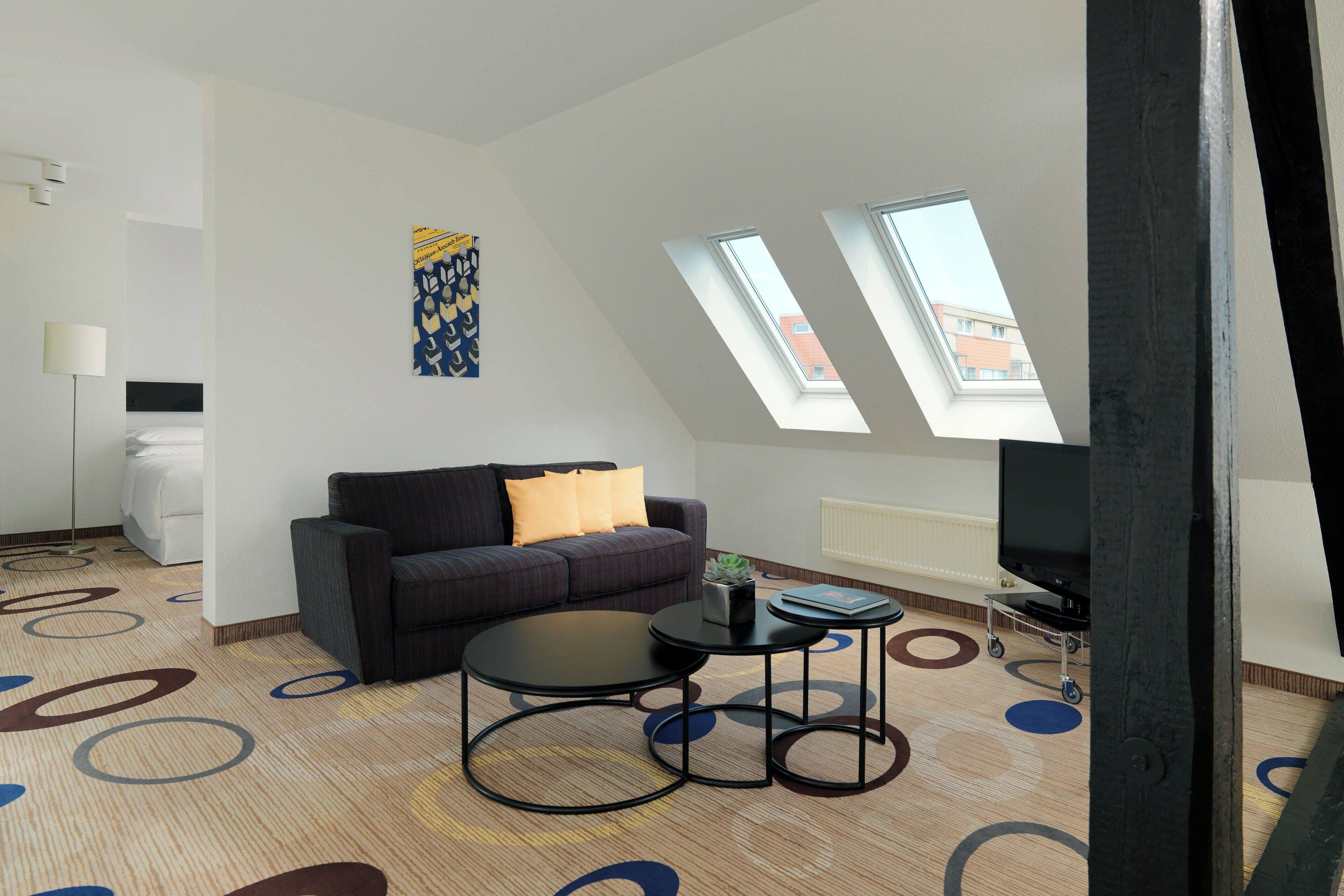 Ein modernes Wohnzimmer mit Sofa, Couchtisch, Fernseher und Dachfenster.