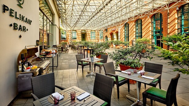 An indoor patio area with tables and chairs, a bar, and potted plants.