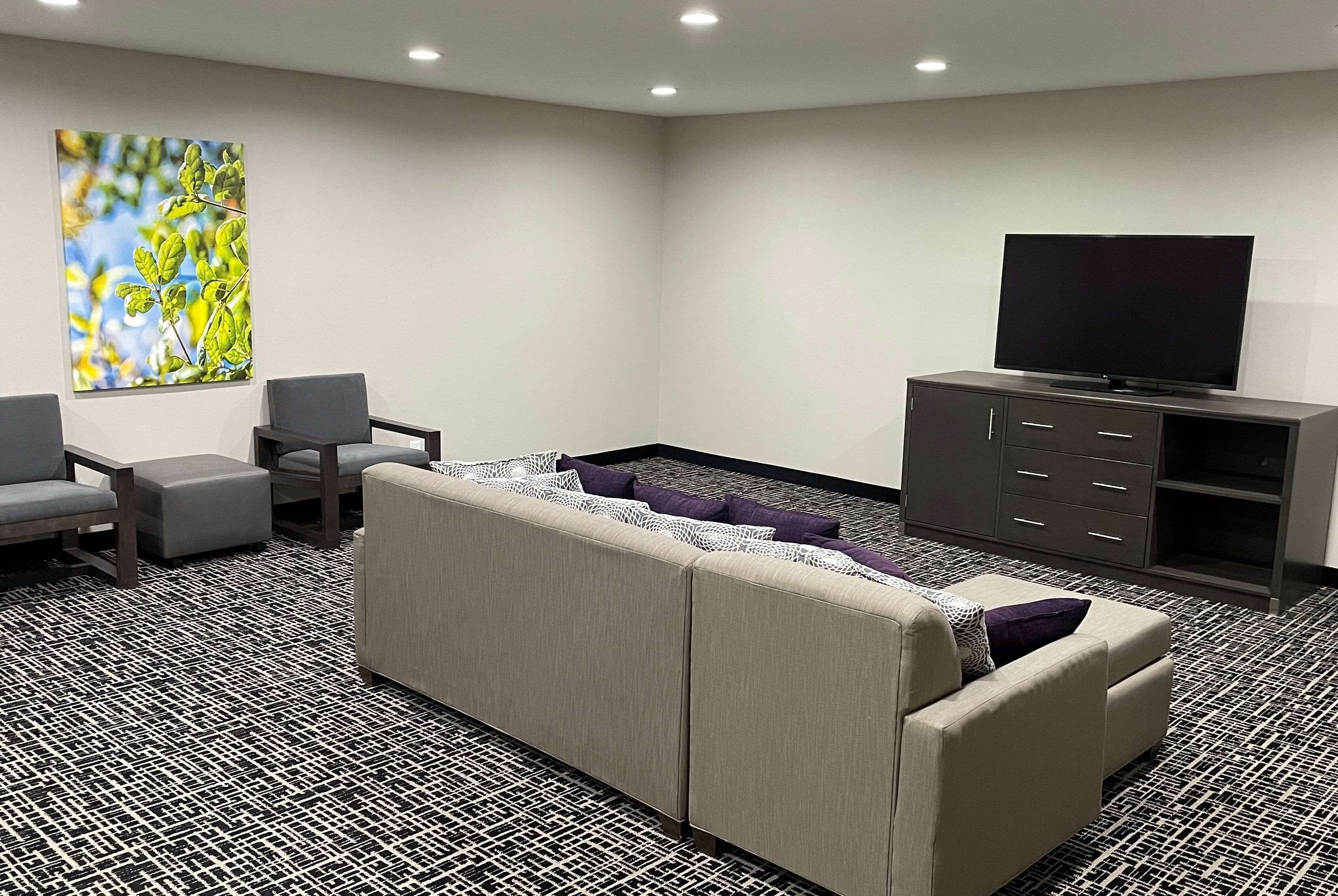 Una sala de estar moderna con sofá, sillones, televisor de pantalla plana y aparador.
