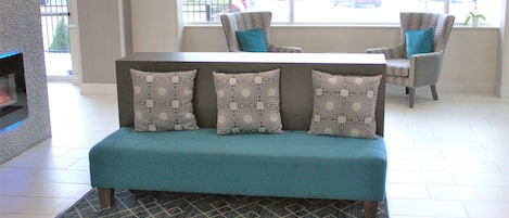 A teal sofa with patterned cushions in a modern interior with a view of the street outside.