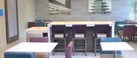 A restaurant with multiple tables and chairs, a tiled floor, and pendant lights.