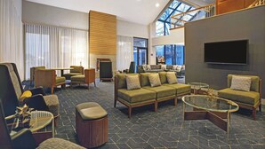A spacious lobby with a high ceiling, a large sofa set, a coffee table, and a staircase leading to an upper level. - Courtyard Chicago Elmhurst/Oakbrook Area (Elmhurst)