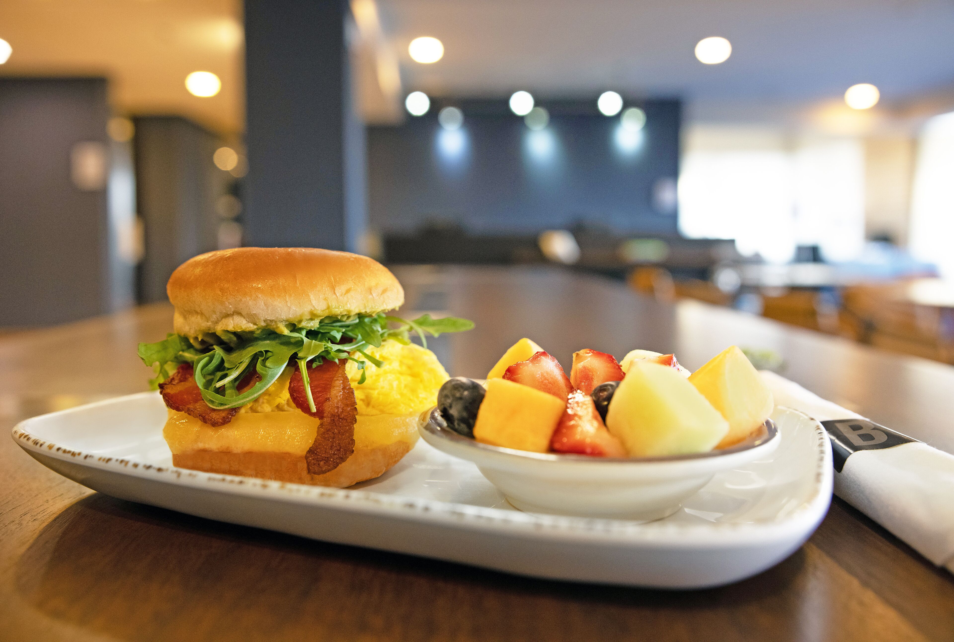 Un plateau repas avec un sandwich et un bol de fruits sur une table dans un restaurant.
