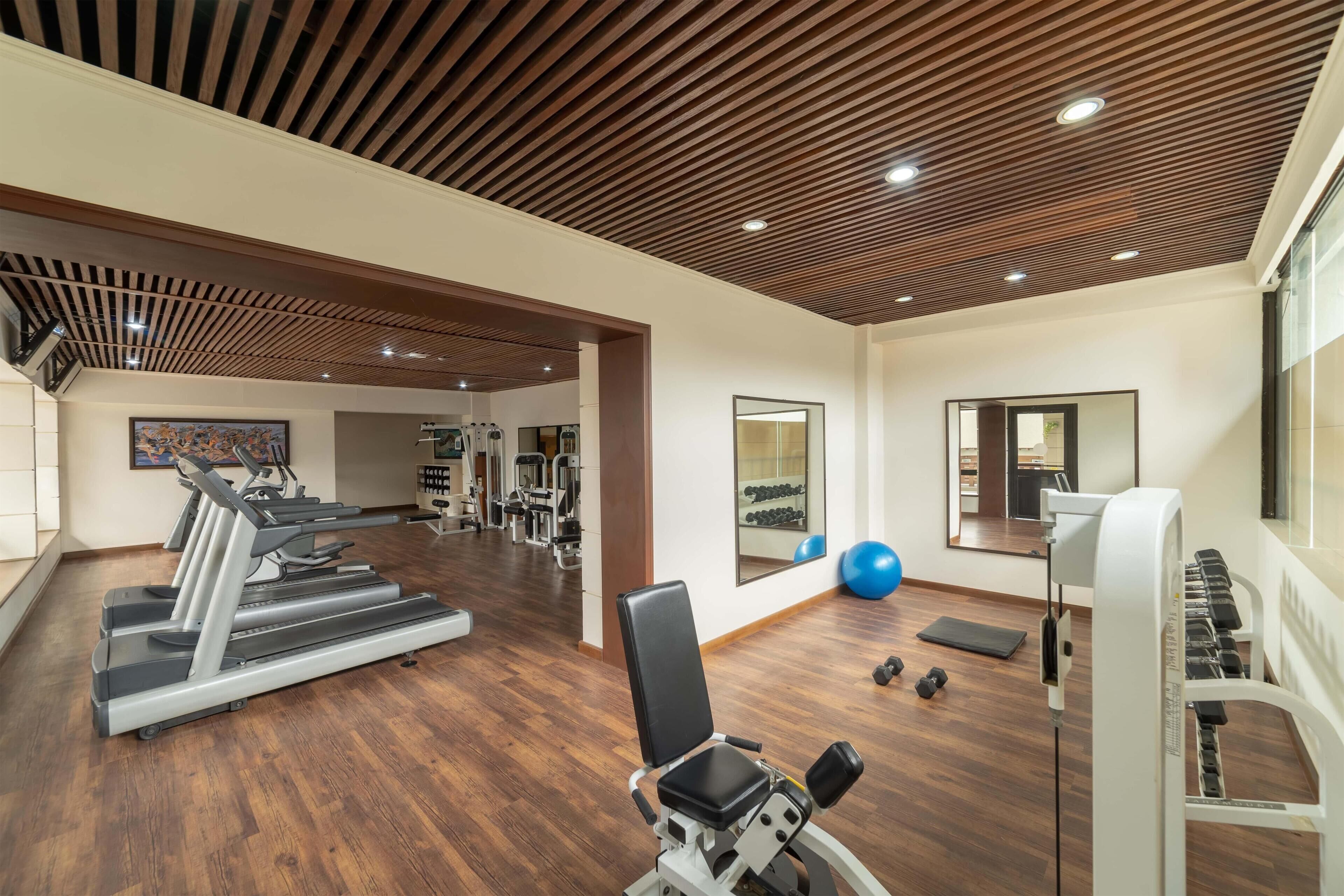Un gimnasio con cintas de correr, máquinas de pesas y pelotas de ejercicio.