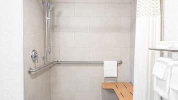 Un área de ducha moderna con barra de apoyo, banco de madera y perchero.