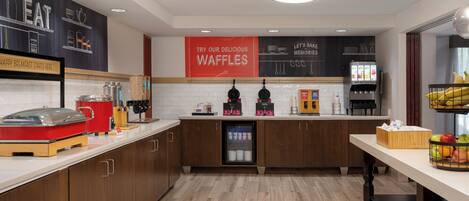 Una cocina moderna con una estación de gofres, una máquina de café y un refrigerador.
