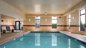 A swimming pool with lounge chairs, a tiled floor, and windows with a view. - Hampton Inn Dubuque (Dubuque)