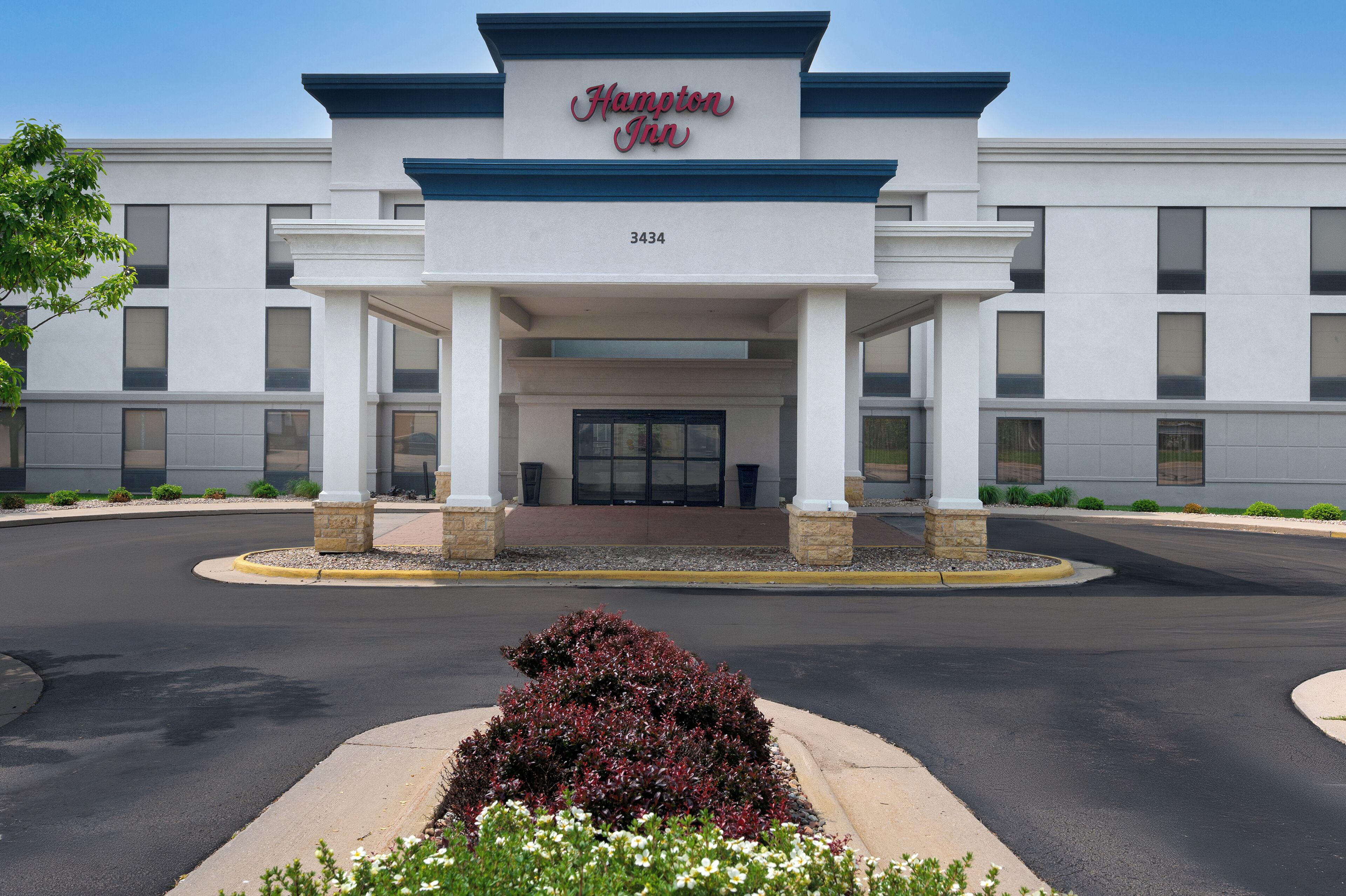 A Hampton Inn hotel with a modern facade, a large entrance, and a landscaped driveway.