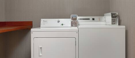 A front-loading washer and dryer stacked on top of each other with a wooden shelf above.