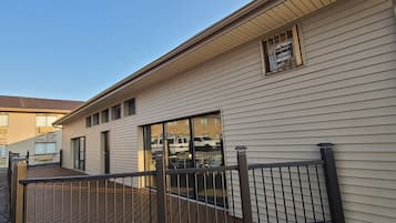 Un edificio residencial con una terraza de madera y un portón metálico.