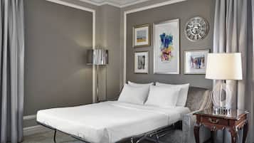 Une chambre d’hôtel avec un lit simple, une table de chevet avec une lampe et des œuvres d’art encadrées accrochées au mur.