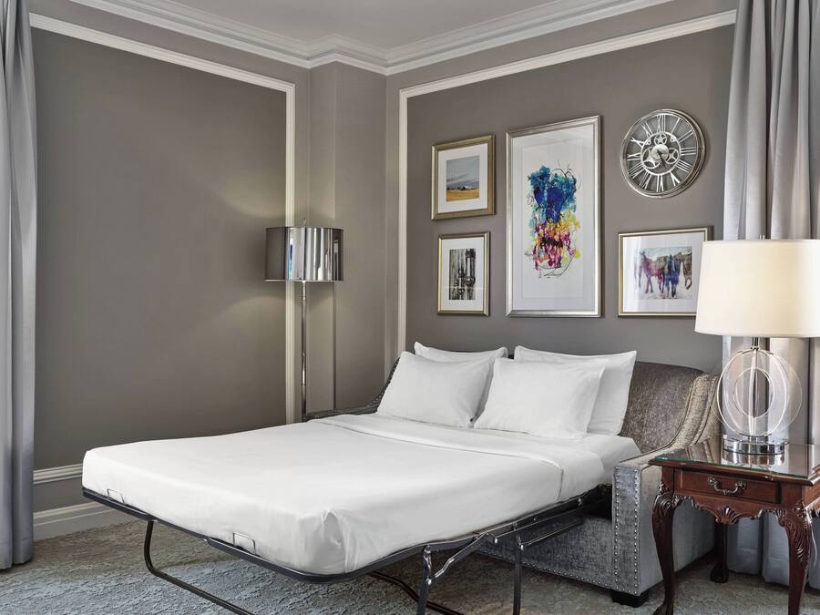 Une chambre d’hôtel avec un lit simple, une table de chevet avec une lampe et des œuvres d’art encadrées accrochées au mur.