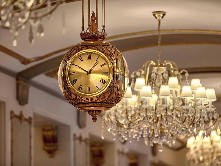 A grand chandelier and an ornate wall clock in a luxurious interior.