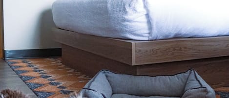A dog bed and a bed in a room with a patterned floor.